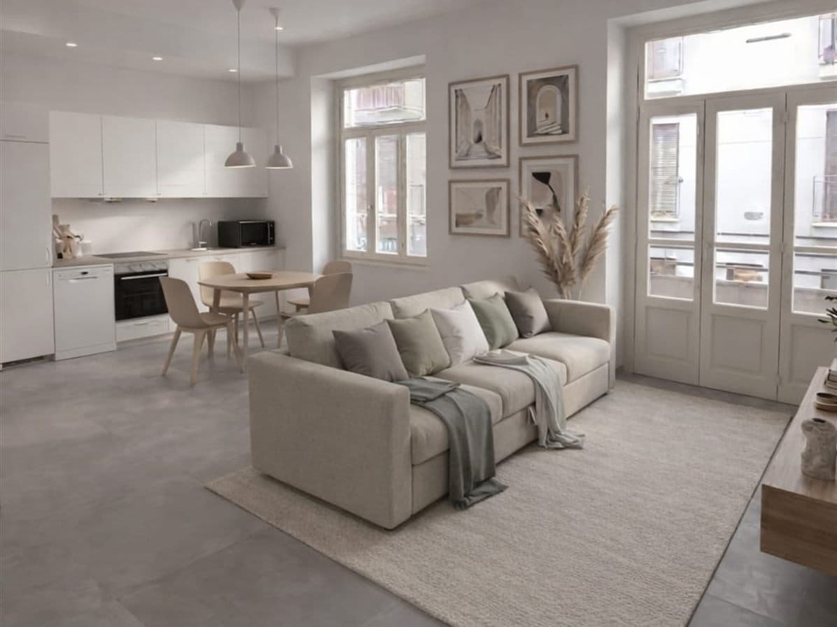 Render fotorealistico dello stesso appartamento dopo home staging: divano beige, cucina chiara, quadri alle pareti